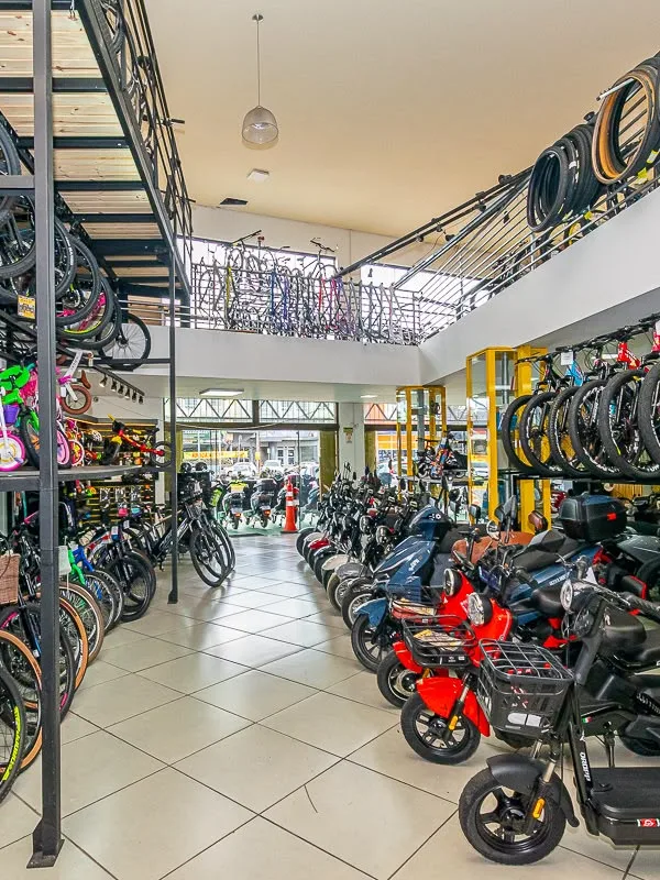 Corredor da loja com bikes nas prateleiras e scooters