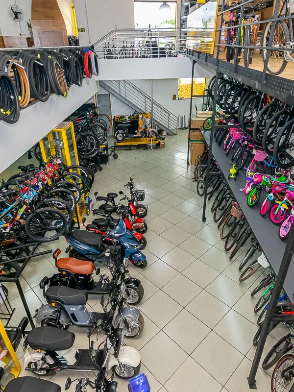 Vista do mezanino com bikes penduradas e scooters lá embaixo